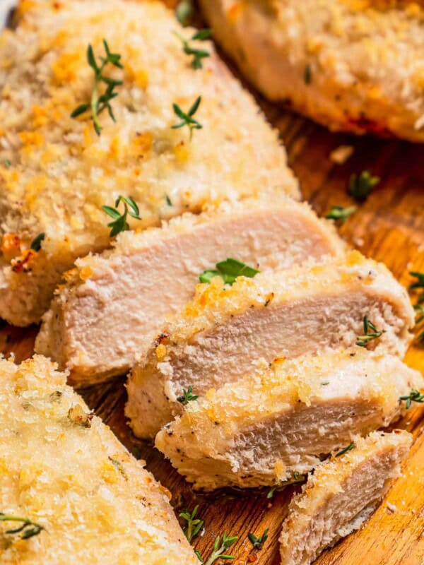 Close up of baked chicken breasts sliced on a cutting board.