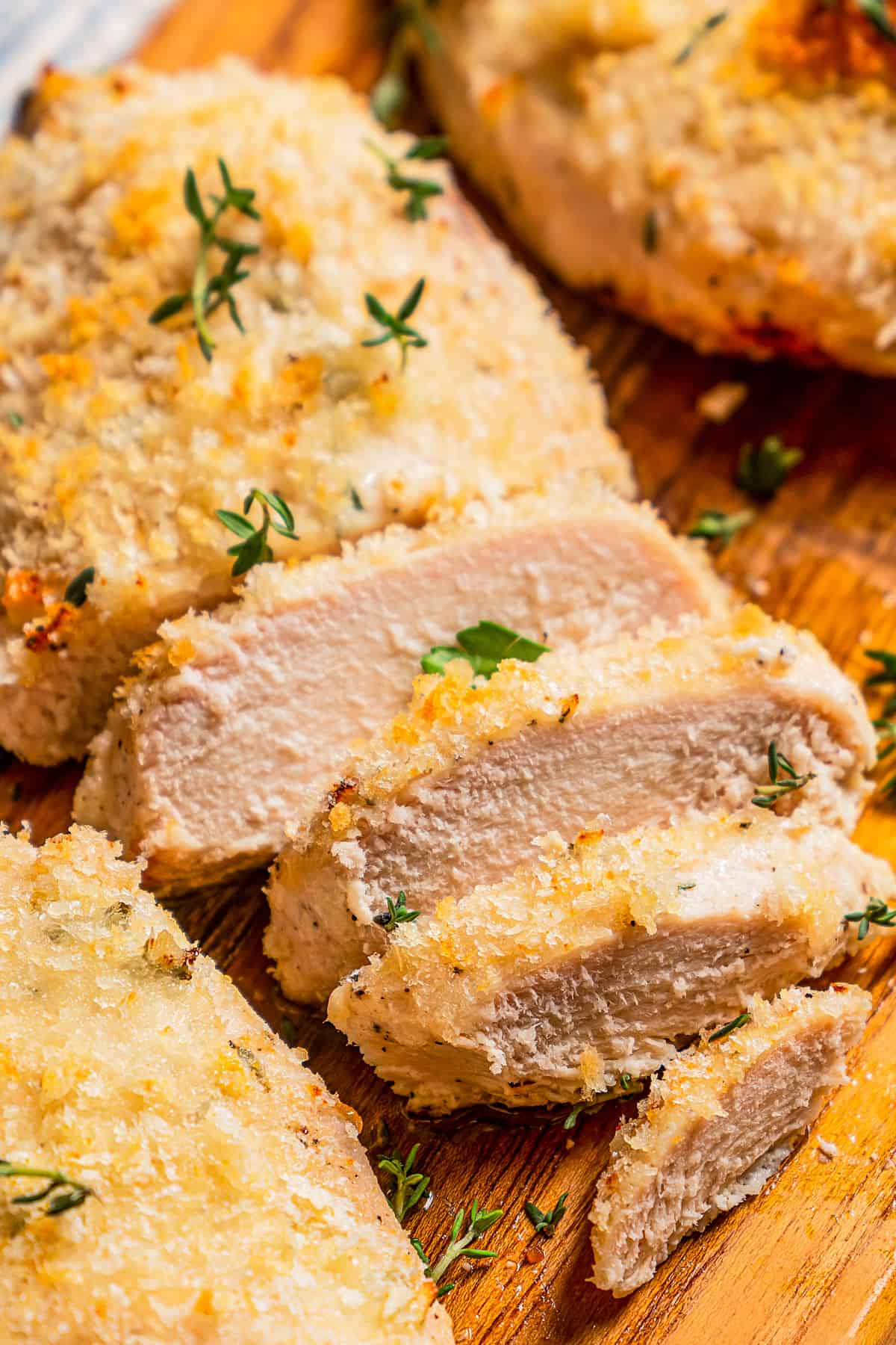 Close up of baked chicken breasts sliced on a cutting board.