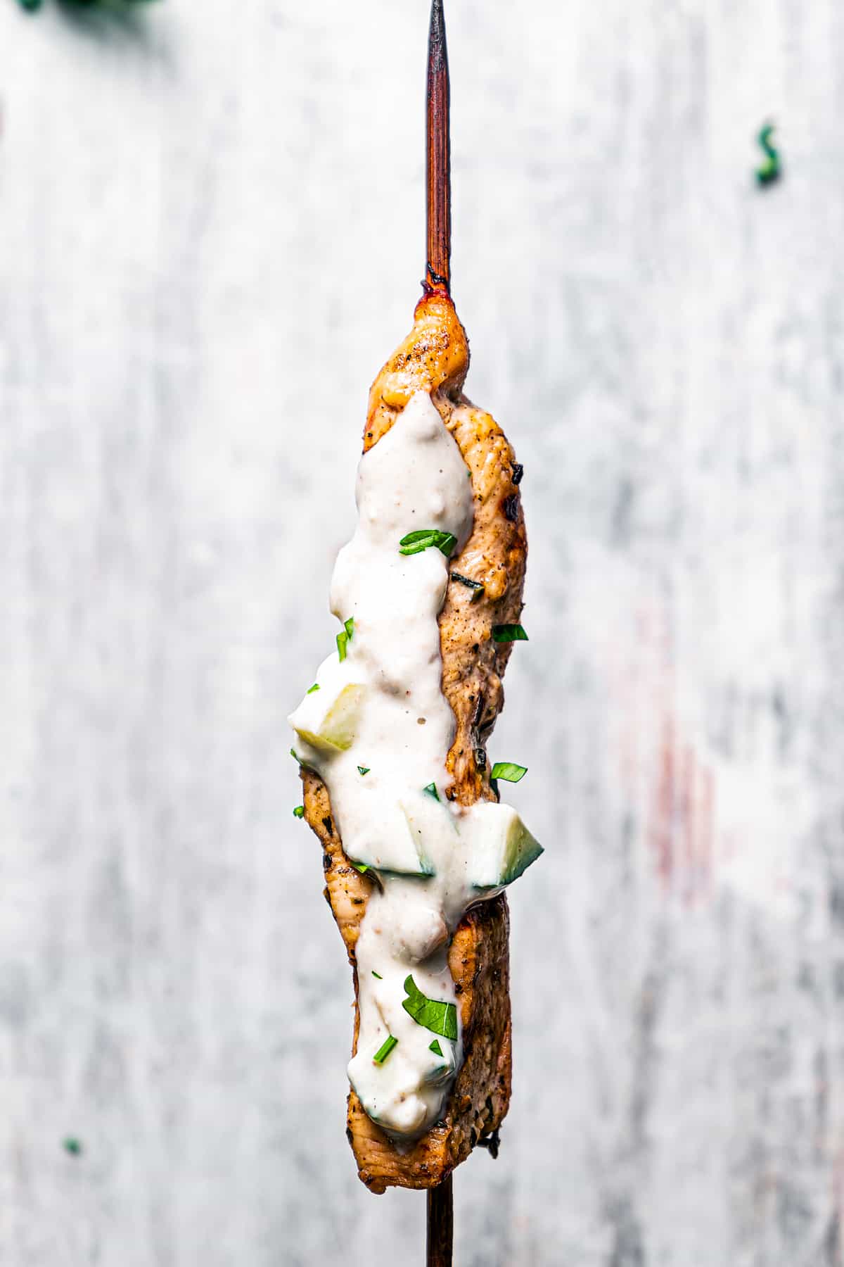 Close up of a chicken skewer brushed with yogurt sauce.