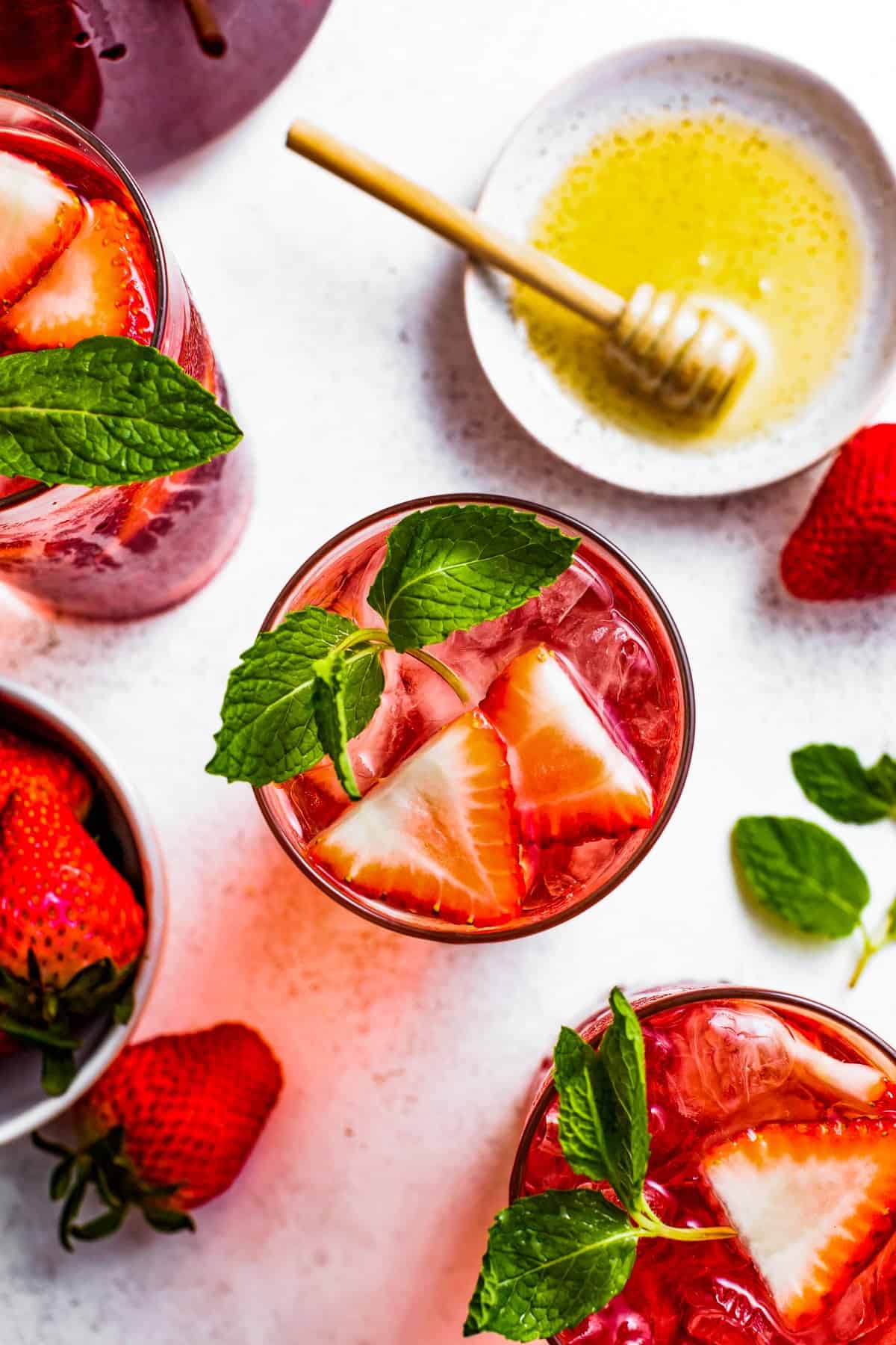 Top view of iced tea topped with mint leaves and halved strawberries.