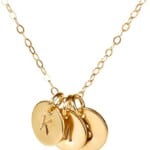A gold necklace with three initials charms