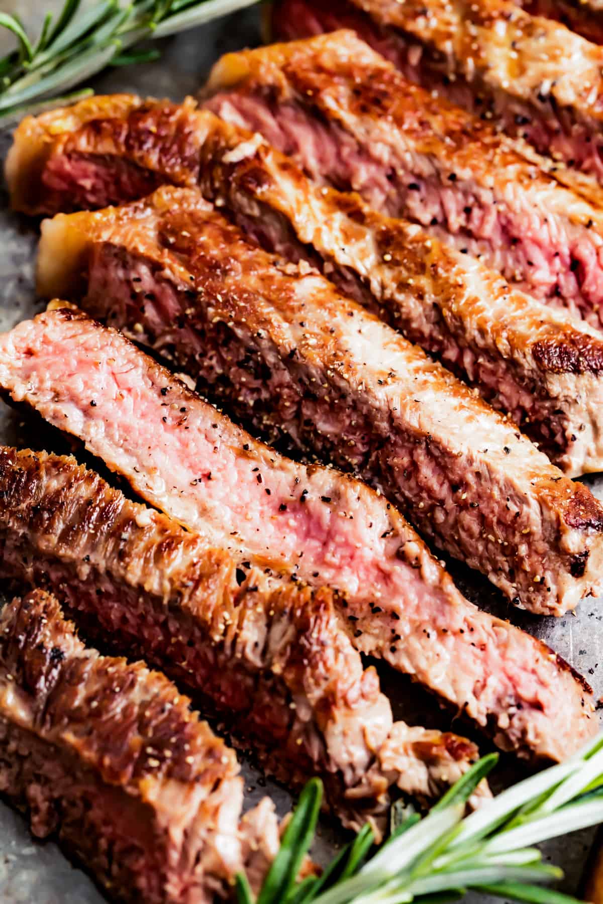 Cook a perfect steak right in the comfort of your home with this simple, flavorful recipe for juicy New York Strip Steak! It takes 15 minutes from start to finish. Closeup of sliced New York strip steak.