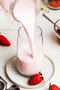 Pouring strawberry milk into a glass.