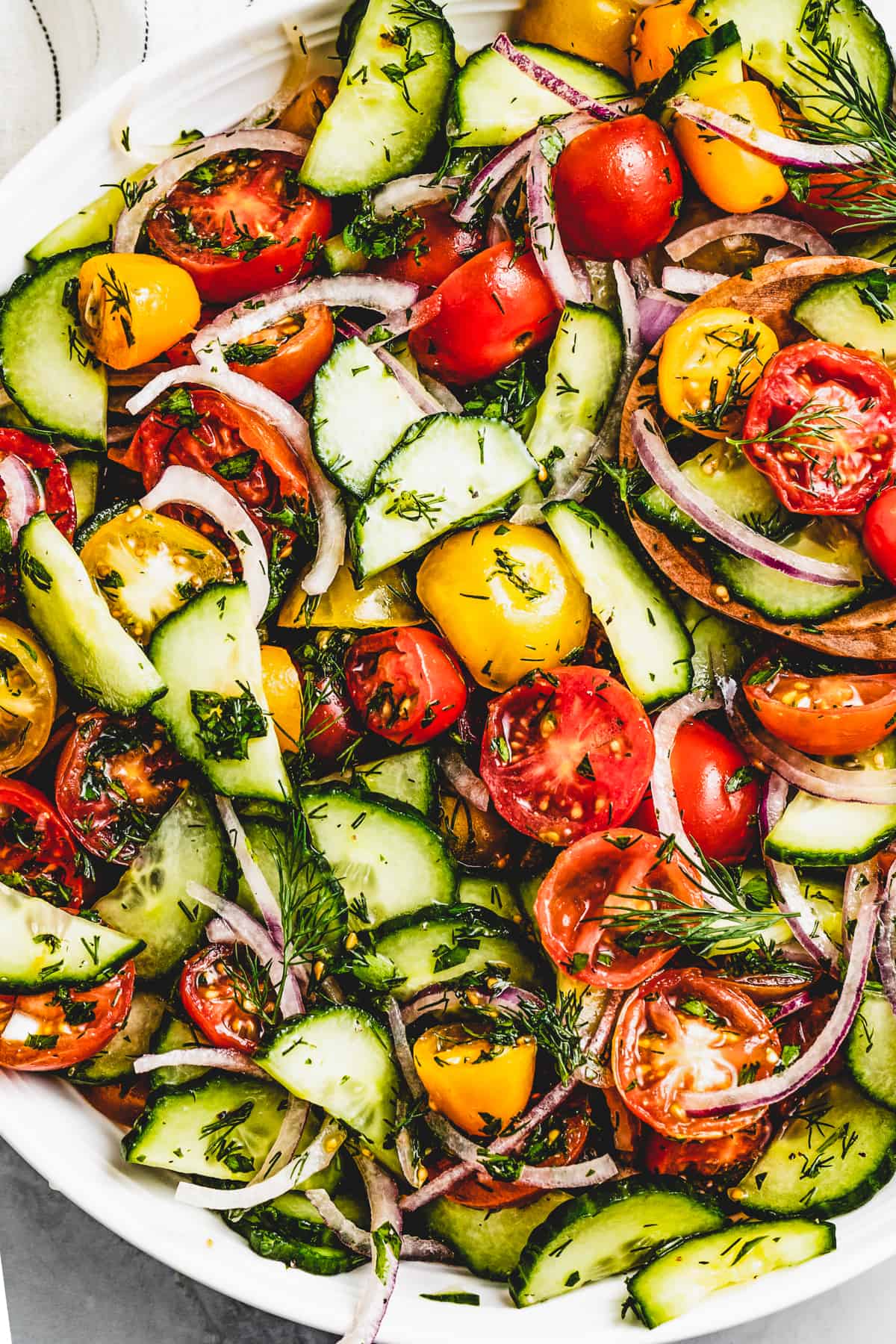 Close-up photo of a tomato and cucumber salad in a round serving bowl.