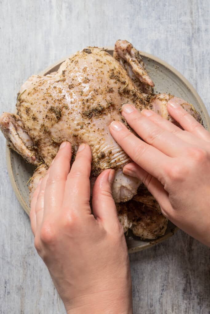 Massaging wet rub into a whole chicken.