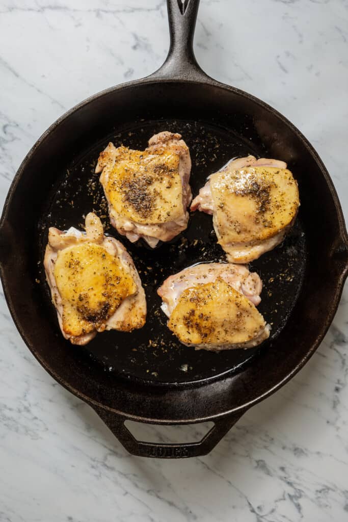 Browning chicken thighs in a pan.