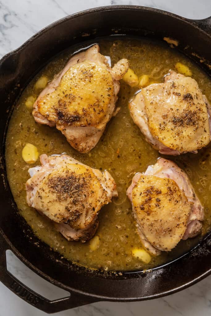 Adding chicken to white wine sauce in a pan.