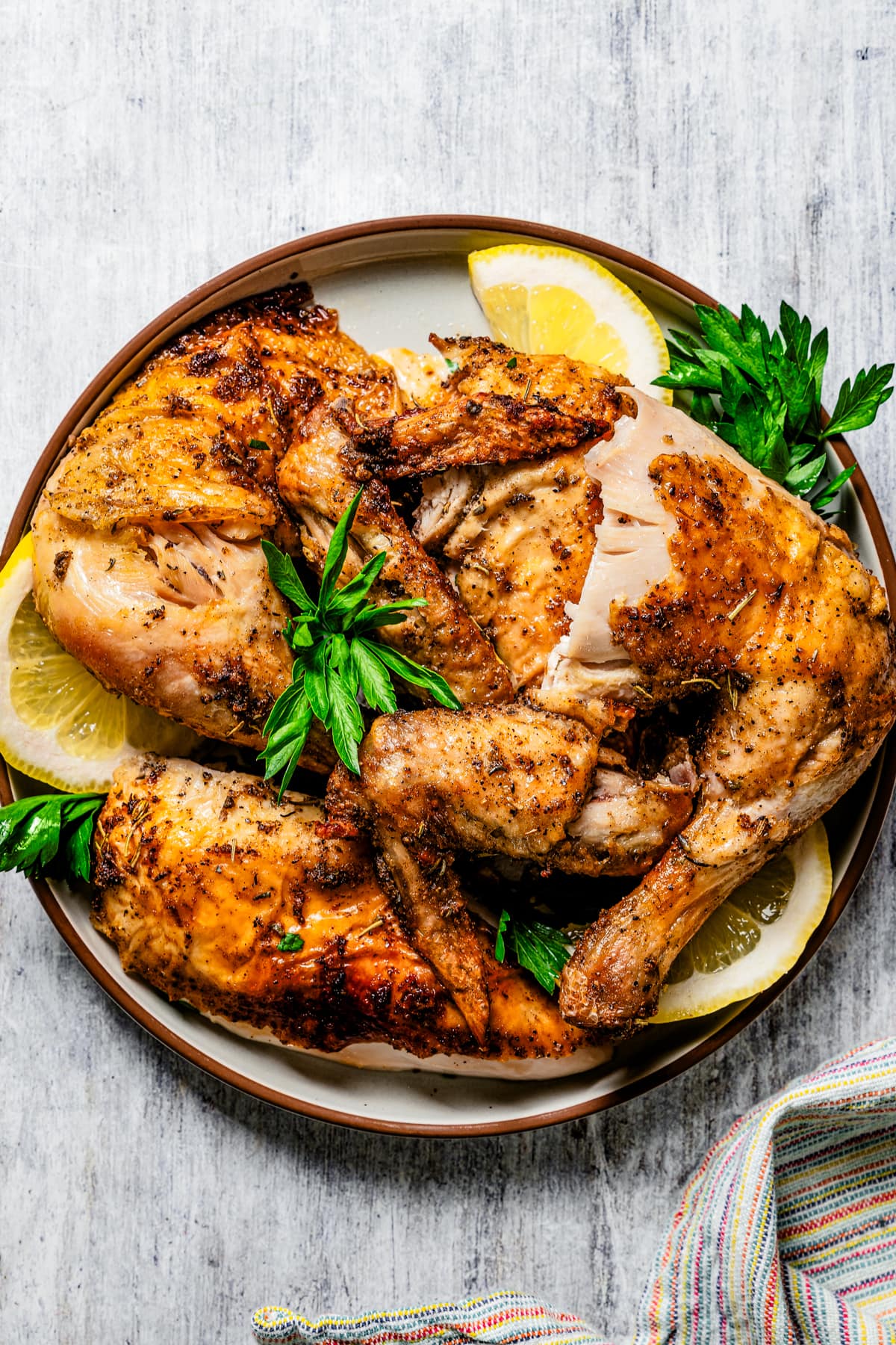 Overhead of air fryer rotisserie chicken cut into pieces and server on a plate.