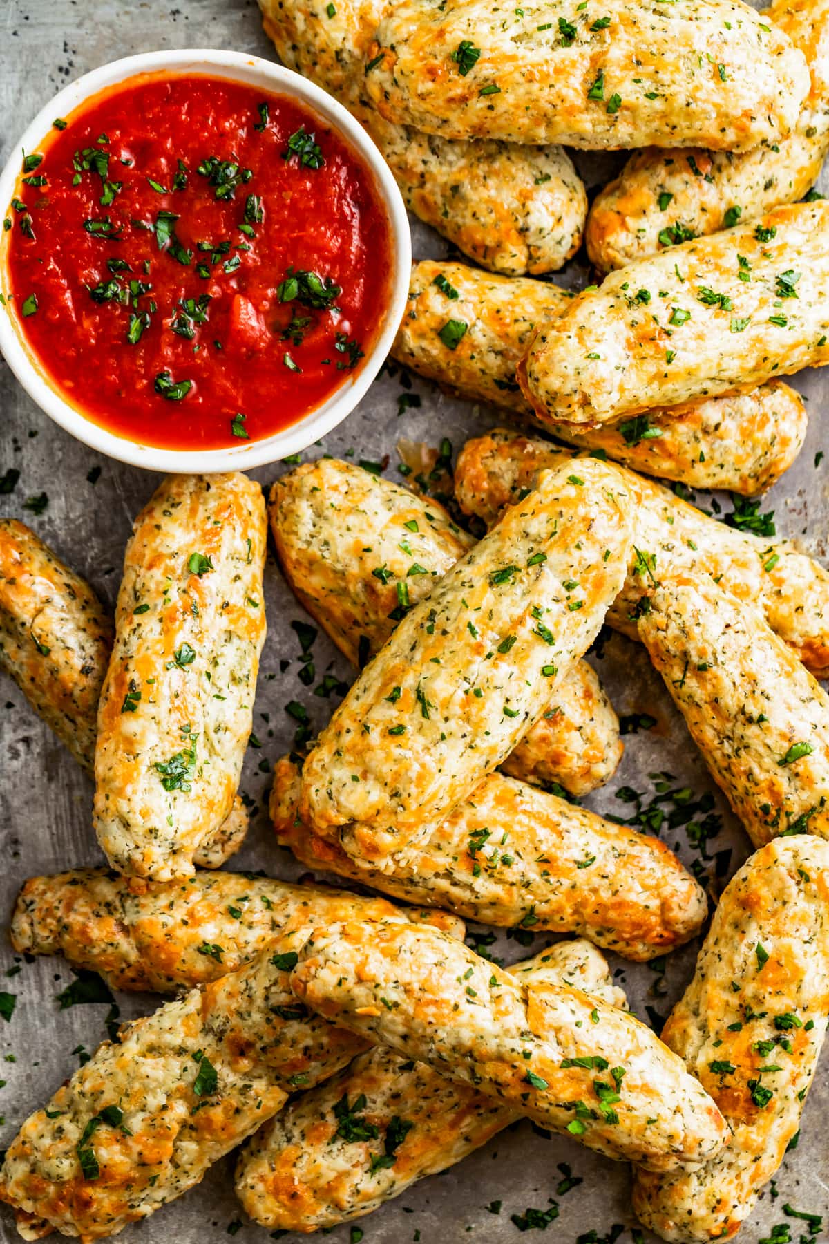 Baked mozzarella sticks on a tray served with a bowl of marinara sauce.