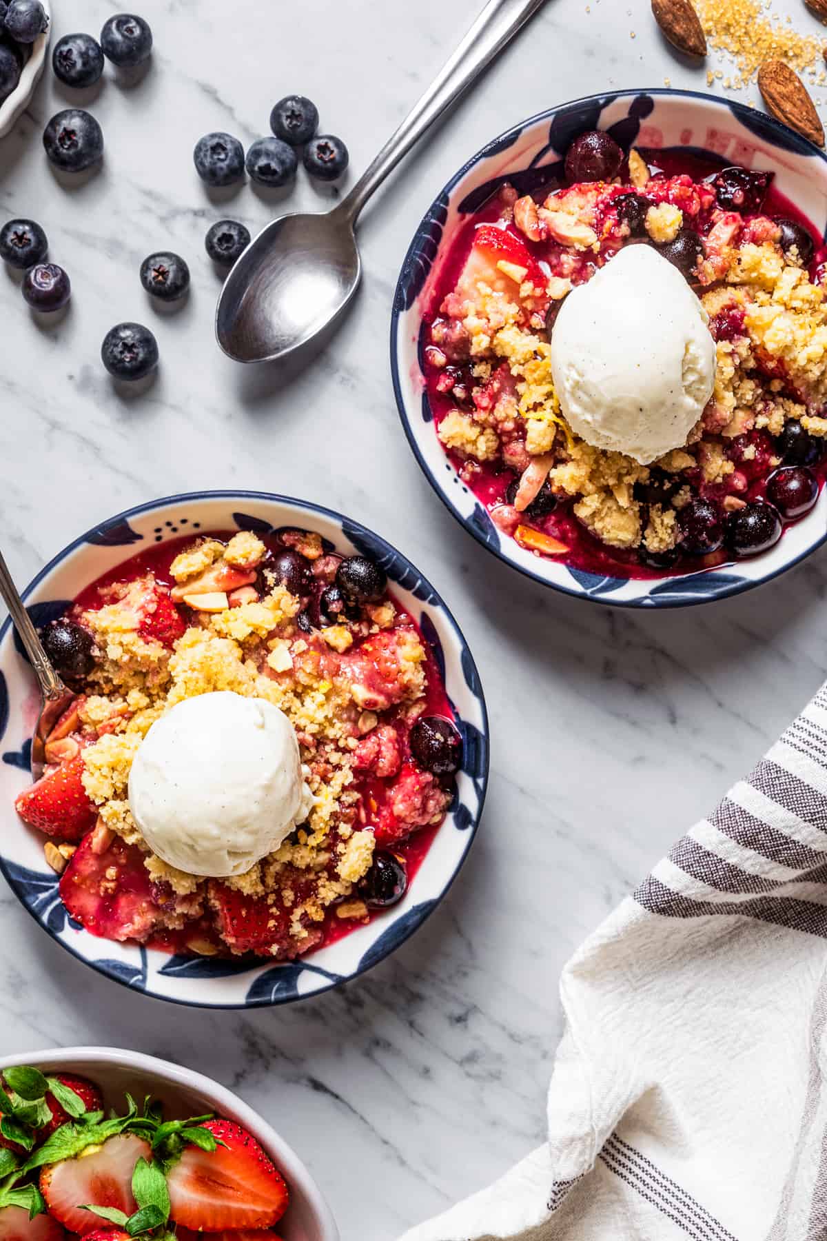 Two bowls of Strawberry Blueberry Crumble topped with ice cream.