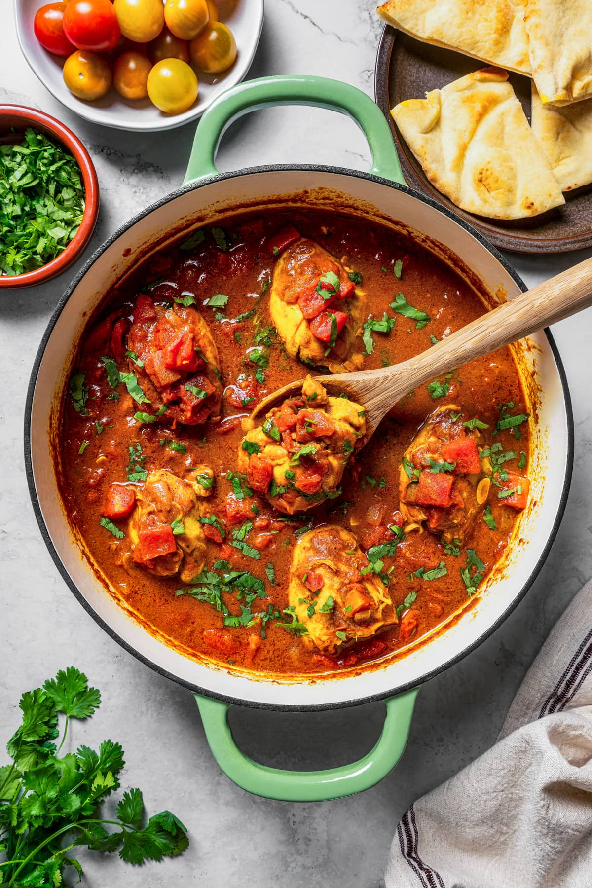 Taking a spoonful of chicken rogan josh out of the pot.