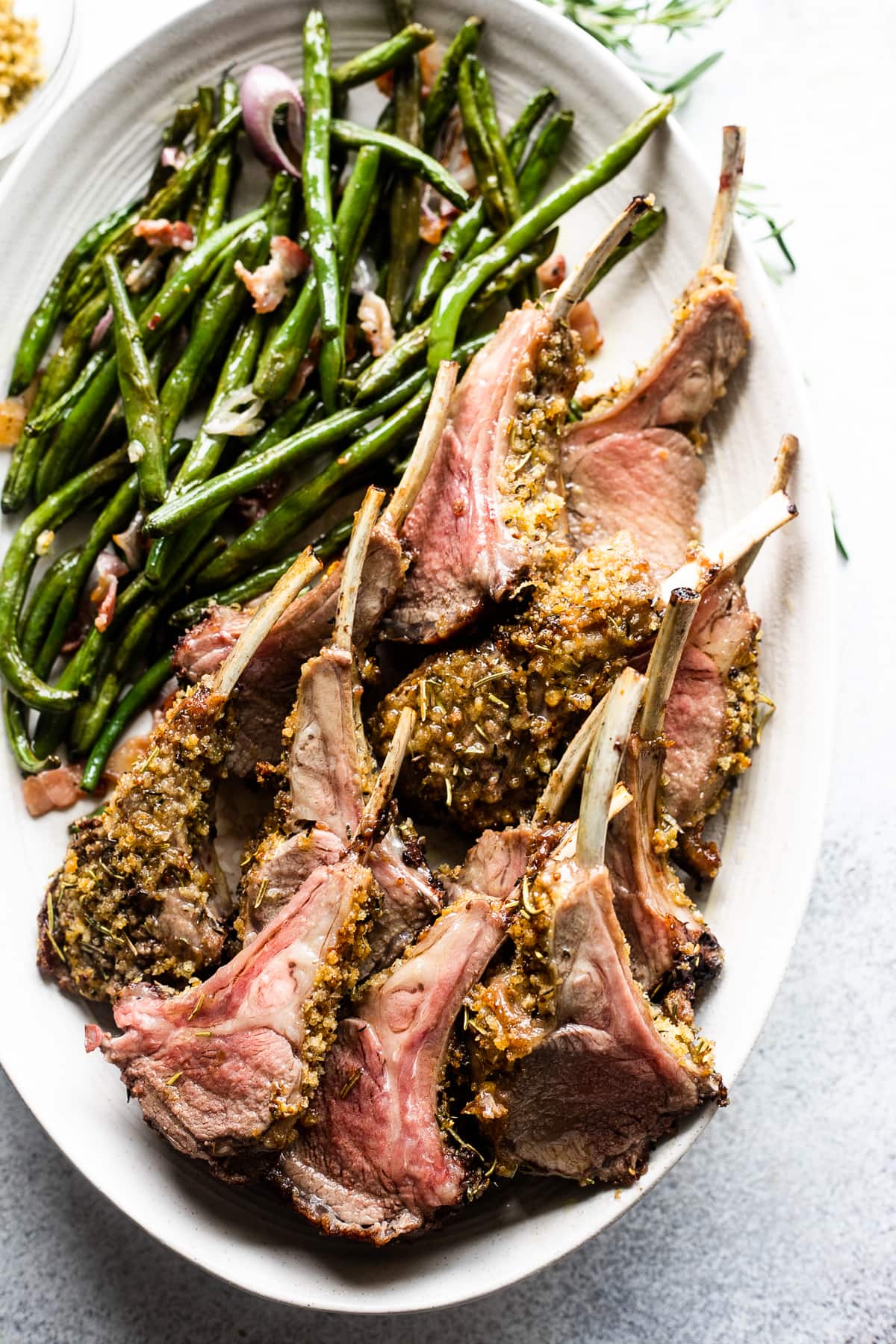 Lamb chops and green beans served on an oval plate.