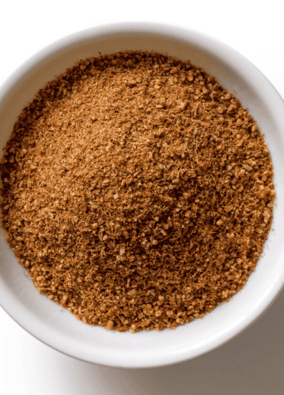 Overhead image of ground cumin in a white bowl.