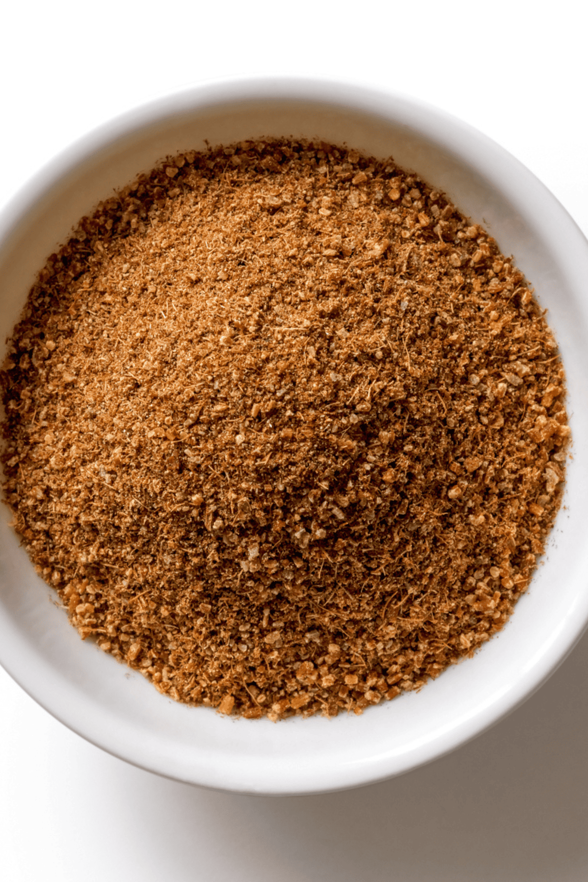 Overhead image of ground cumin in a white bowl.