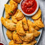 A plate with homemade Pierogi and dipping sauce.