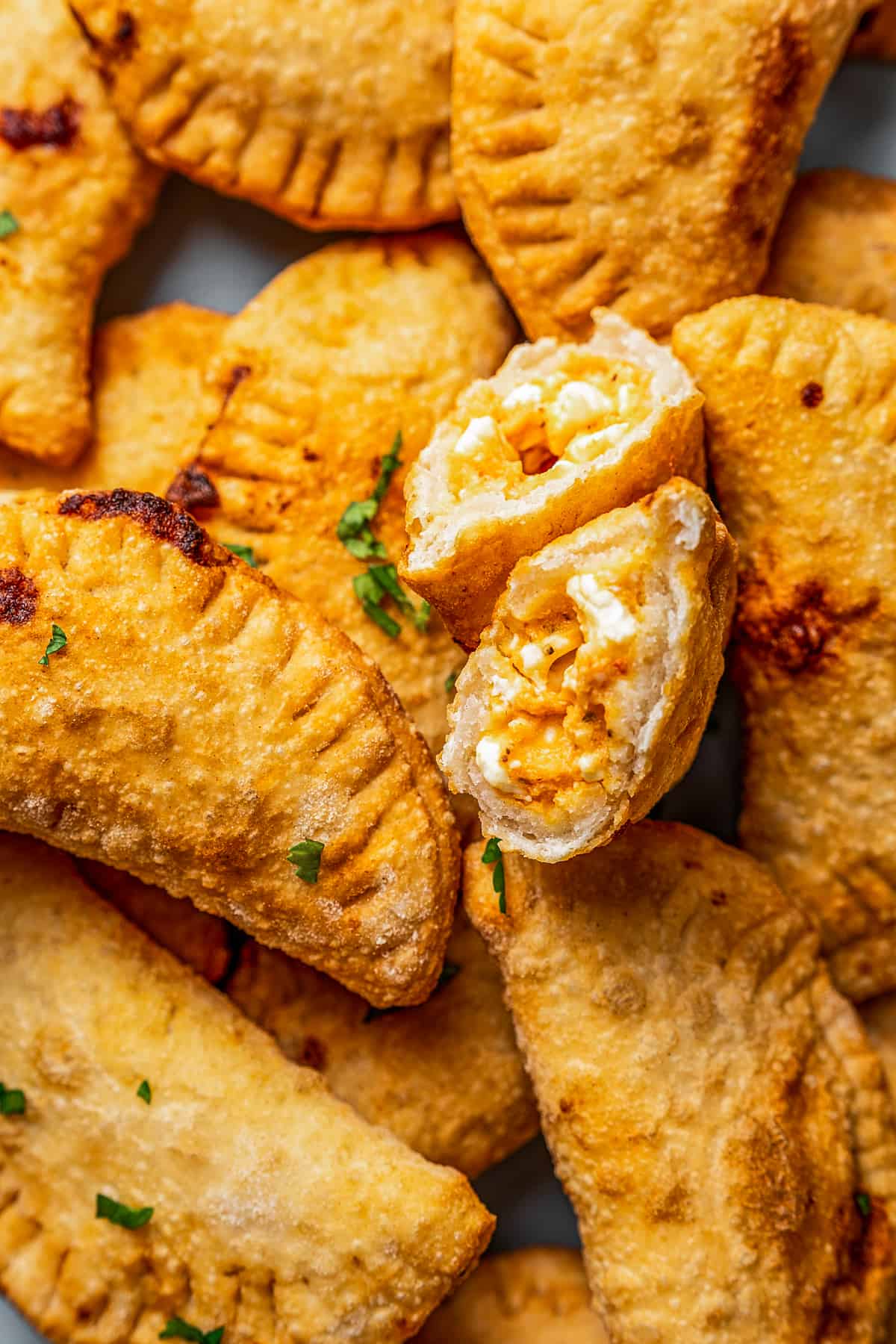 Close-up of a pile of pierogi with a bite taken out of one.