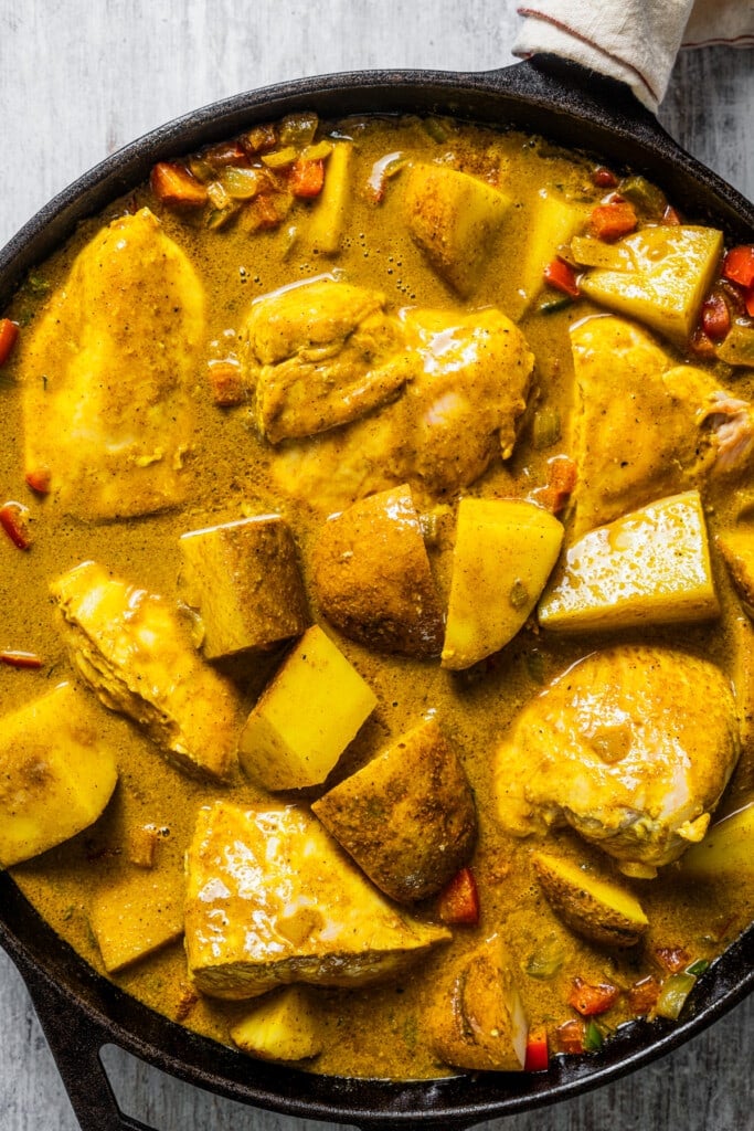 Adding the potatoes and chicken back to the pan to finish Jamaican curry chicken.