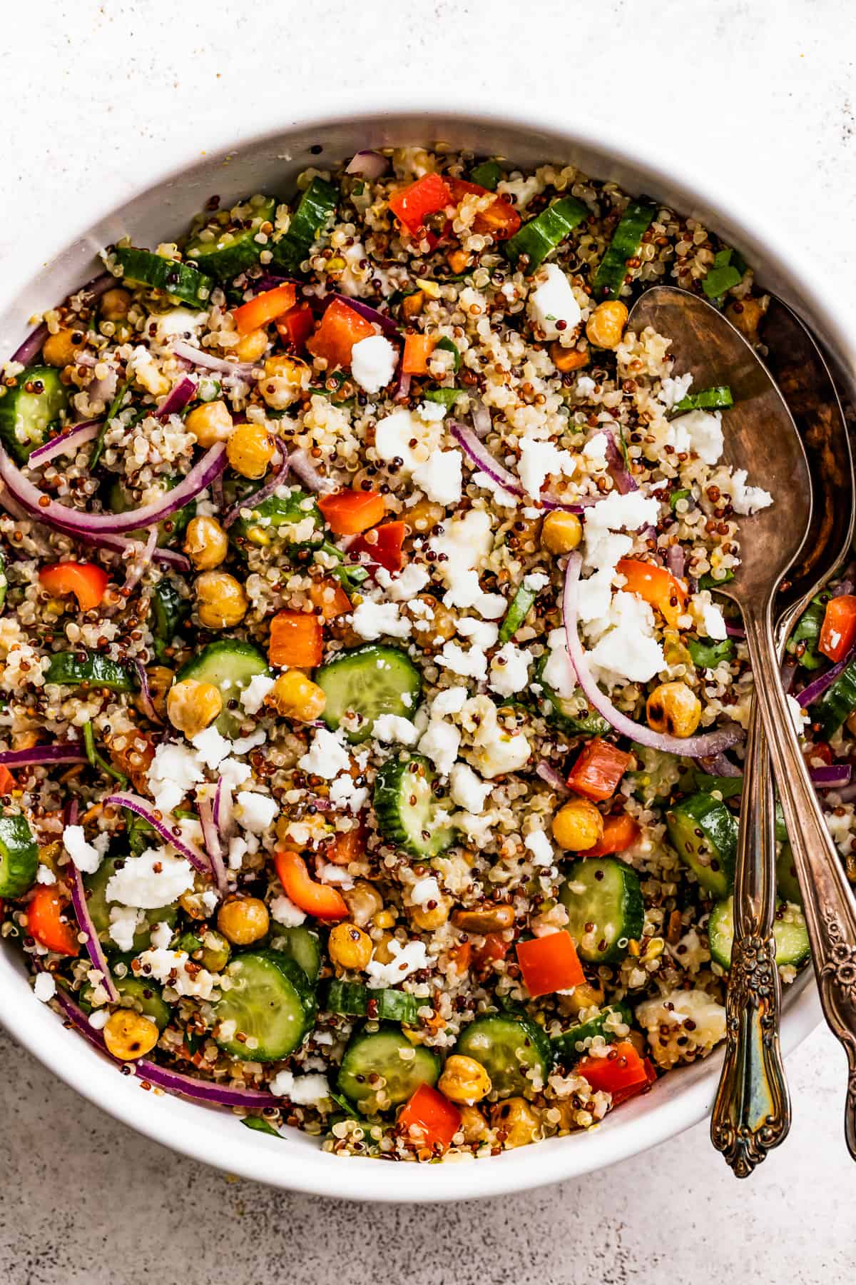 A bowl with Tri-color quinoa salad tossed with crunchy chickpeas and drizzled with homemade dressing.