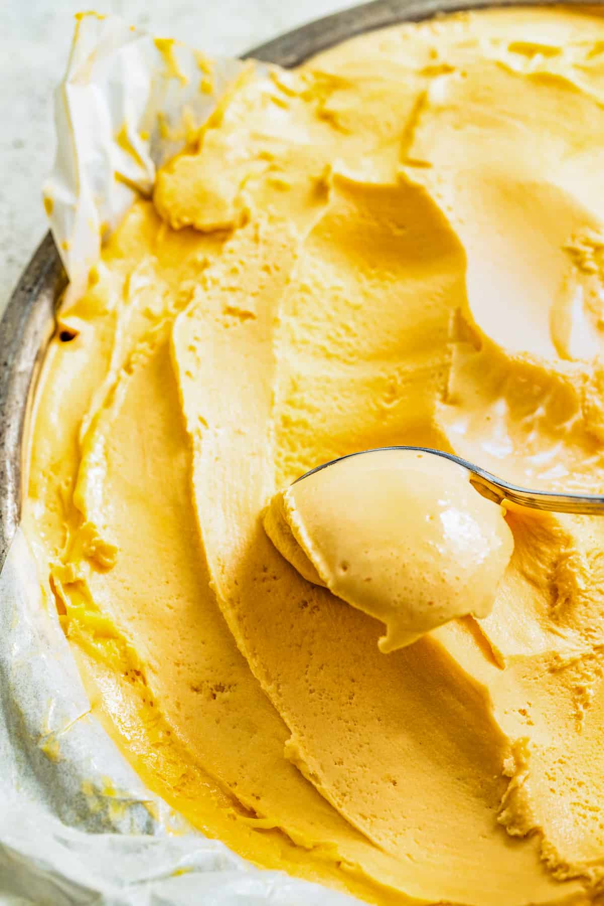 Gliding through mango ice cream in a pan with a spoon.