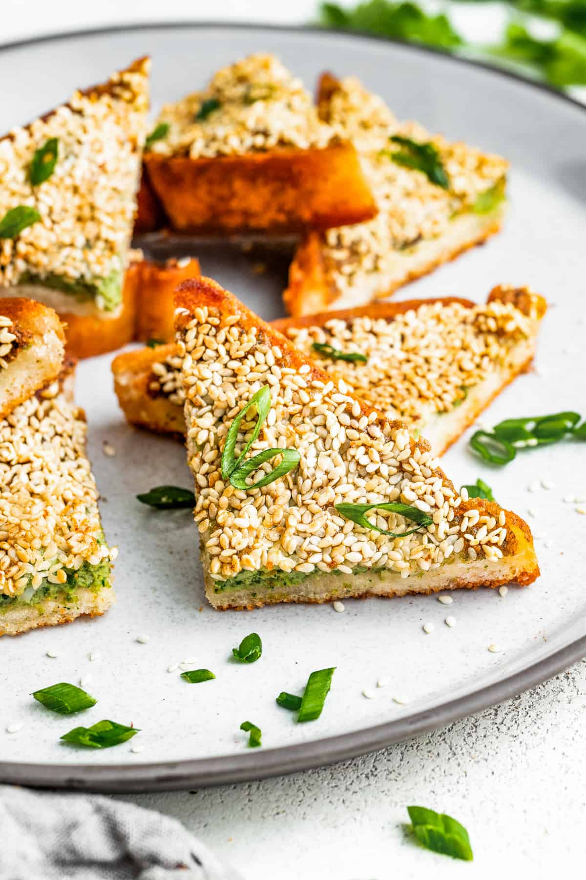 Shrimp toast arranged on a plate and garnished with sliced green onions.