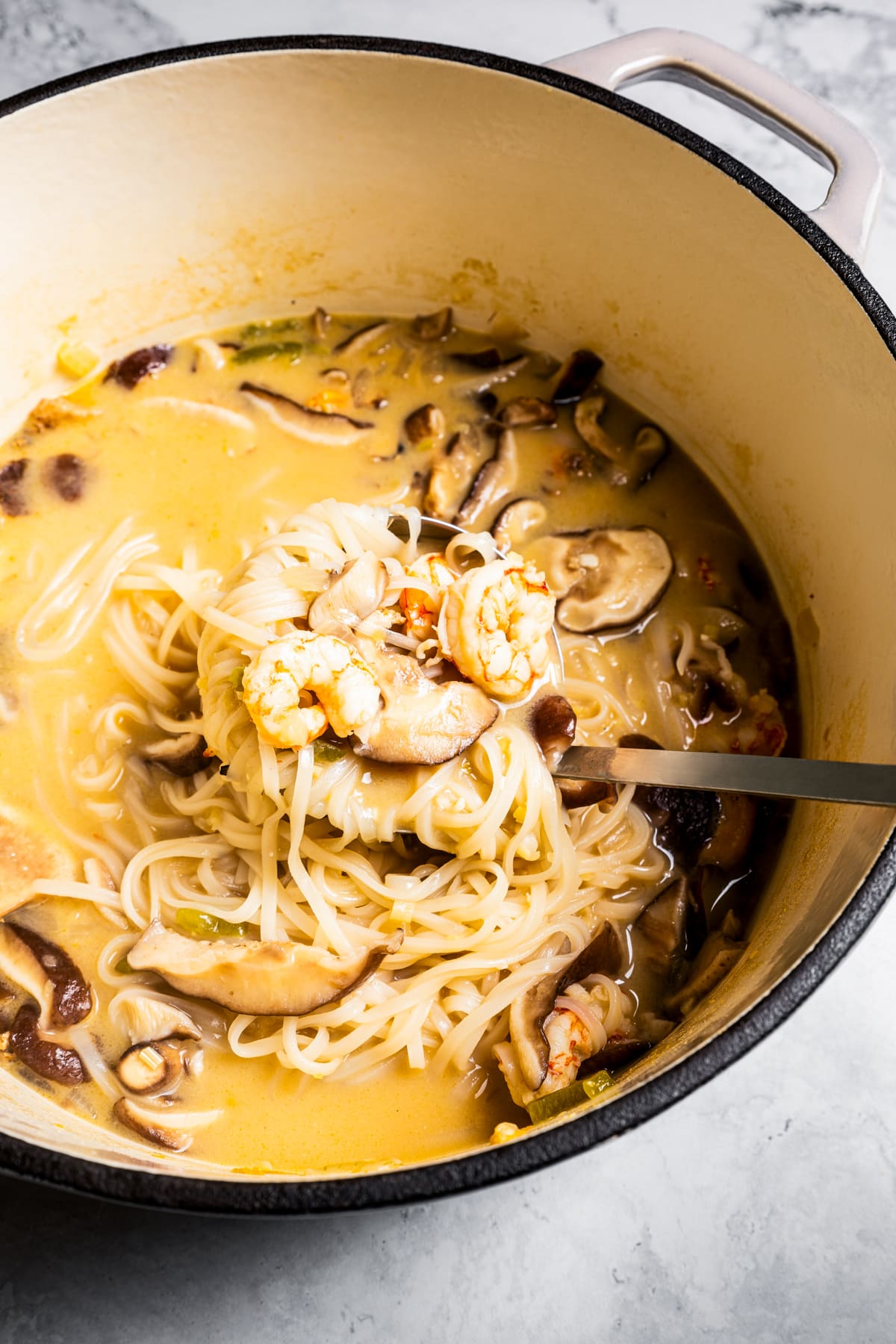 Serving tom yum noodle soup with a ladle.