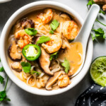 Tom yum noodle soup in a bowl with a lotus spoon.