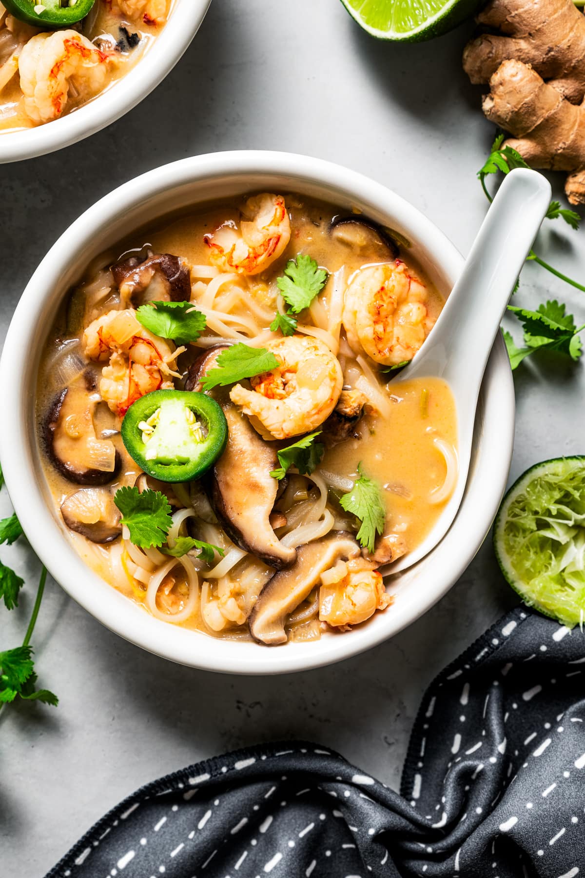 Tom yum noodle soup in a bowl with a lotus spoon.