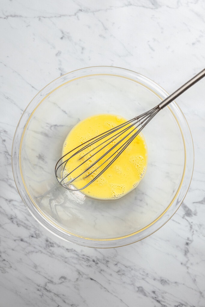 Whisking together eggs and milk in a bowl.
