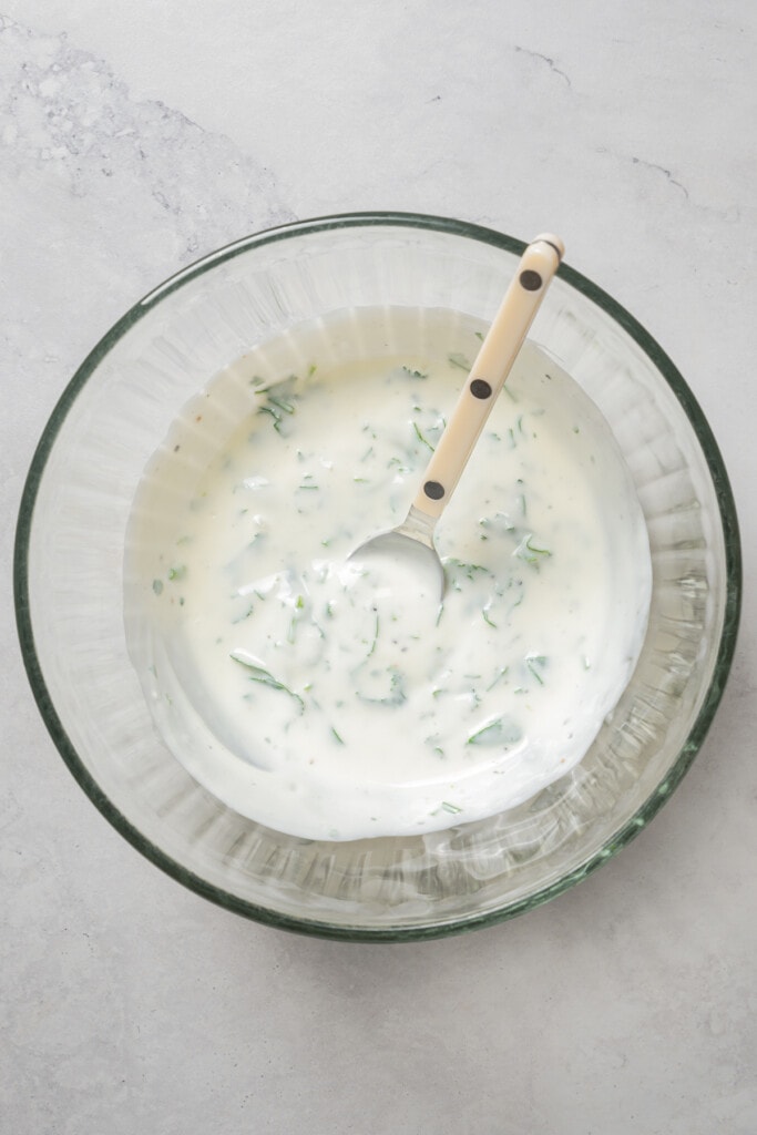 Cilantro-yogurt sauce in a bowl with a spoon.