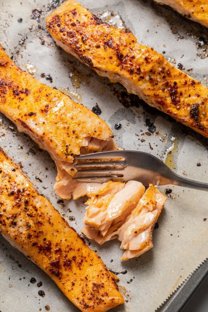 Cutting into baked salmon with a fork.