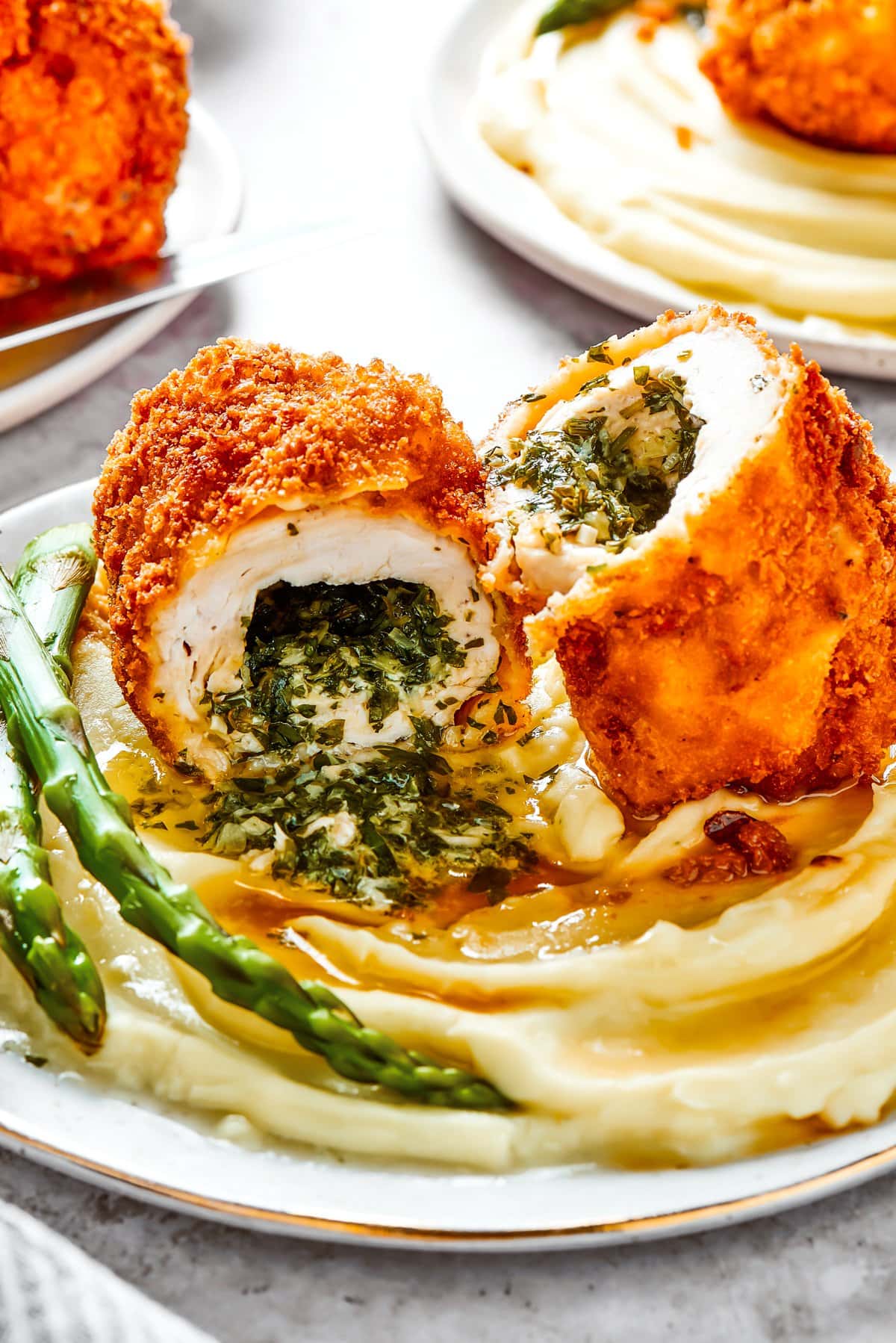 Halved chicken Kiev served over mashed potatoes and a side of asparagus.