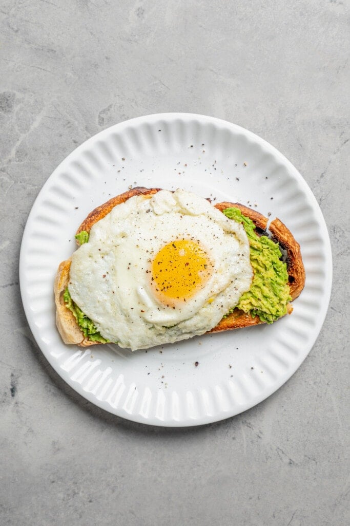 Overhead image of avocado toast with a sunny side up egg on top.
