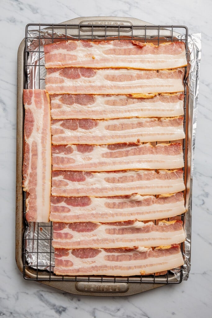 Arranging bacon on a wire rack set above a baking sheet.