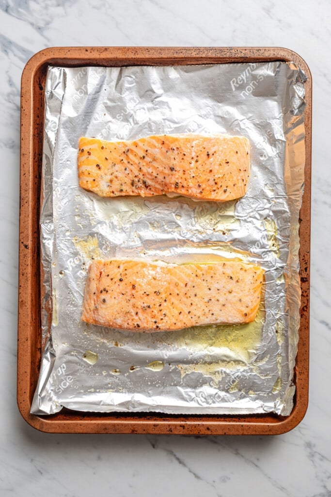 Roasted salmon on a sheet pan lined with aluminum foil.