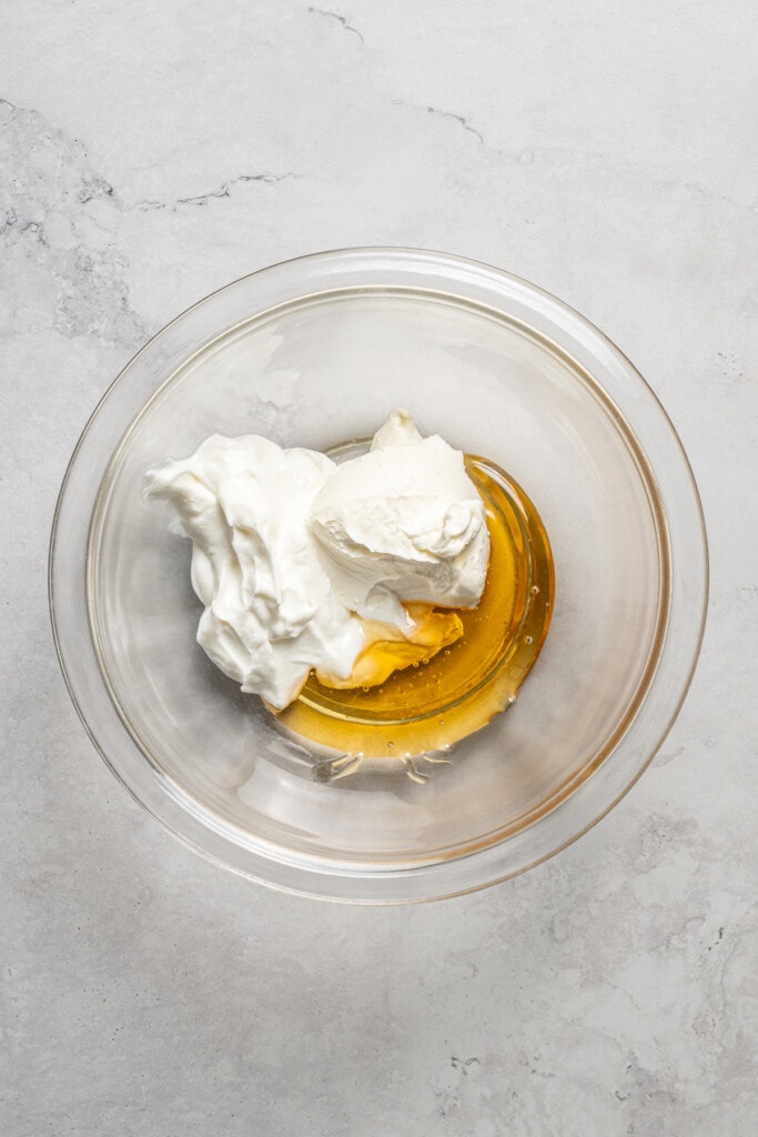 Adding ingredients for cream cheese-greek yogurt dressing to a mixing bowl.