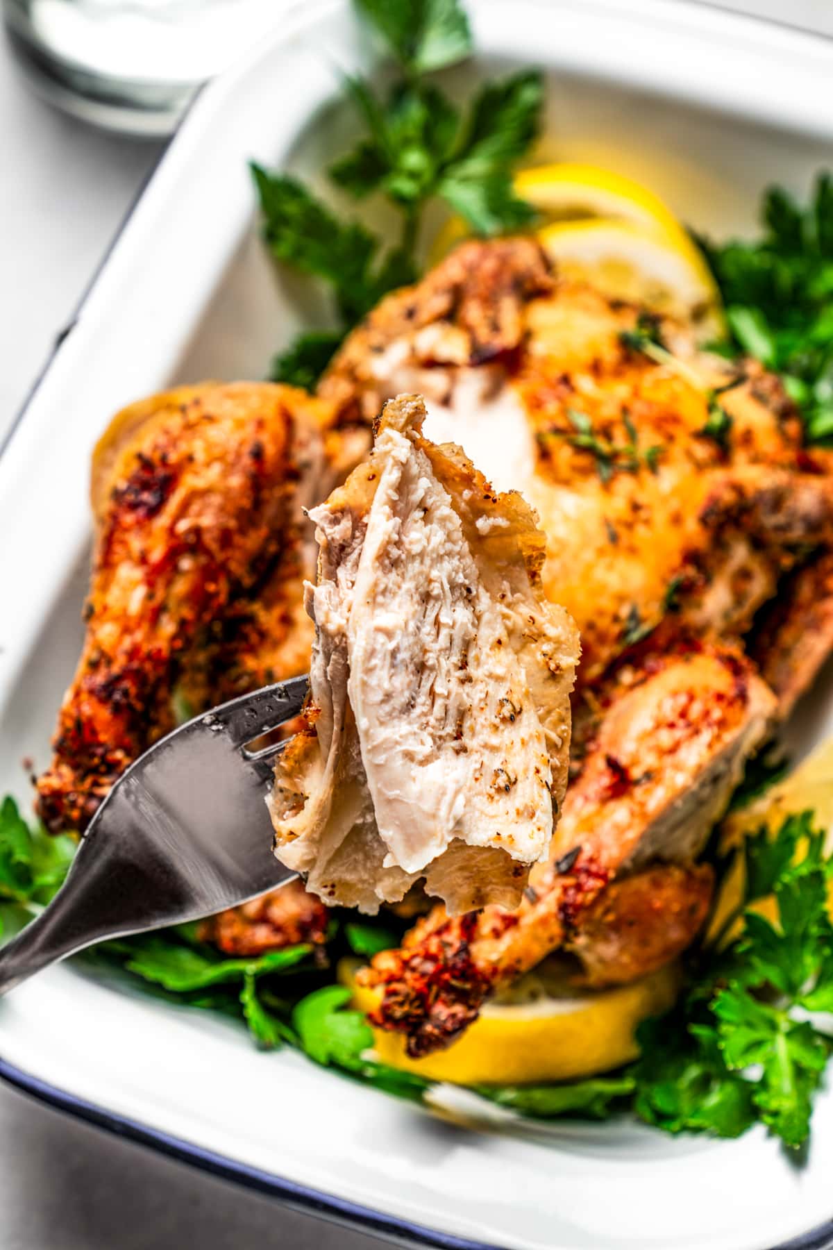 A fork taking a bite out of crispy air fryer cornish game hen.