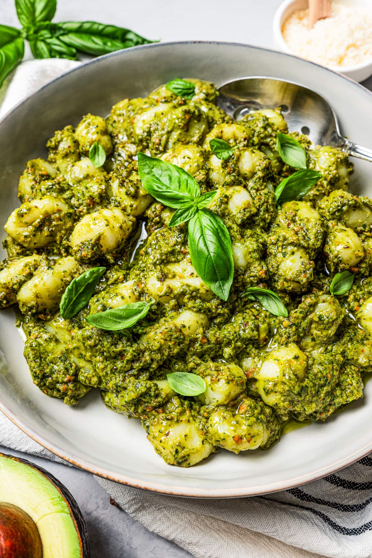 Overhead image of avocado pesto pasta served on a dinner plate and garnished with basil leaves.