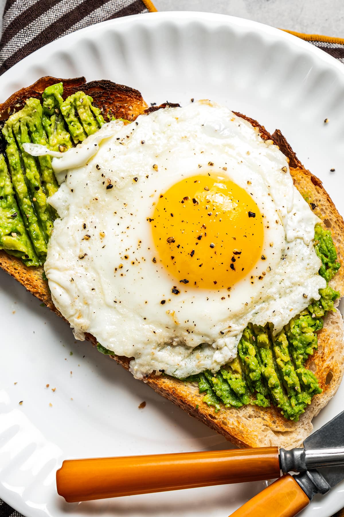 Close-up image of Avocado toast with an egg on top and served on a plate.