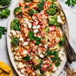 Overhead image of broccoli cauliflower salad on a serving plate with a serving spoon.