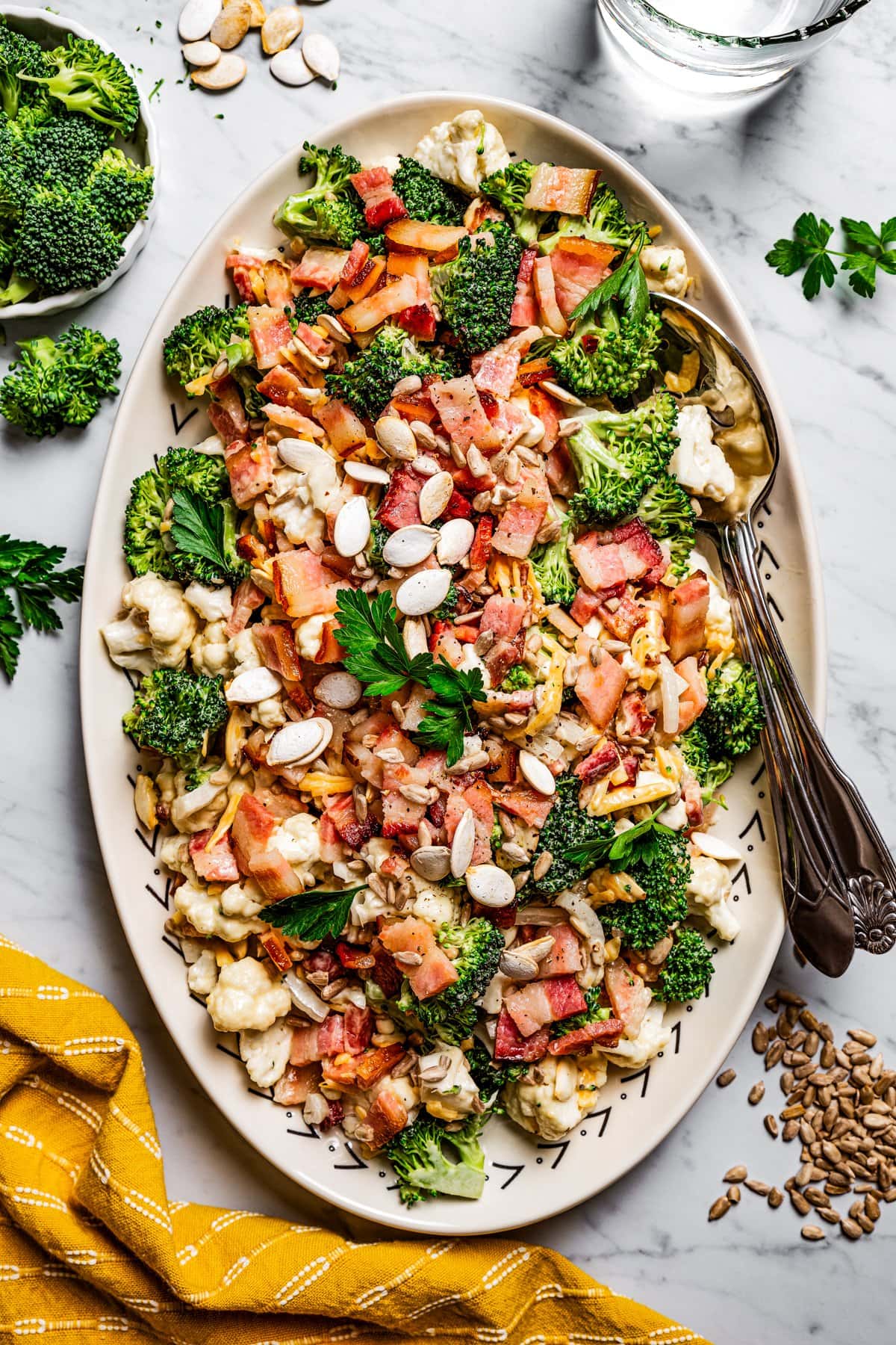 Overhead image of broccoli cauliflower salad on a serving plate with a serving spoon.