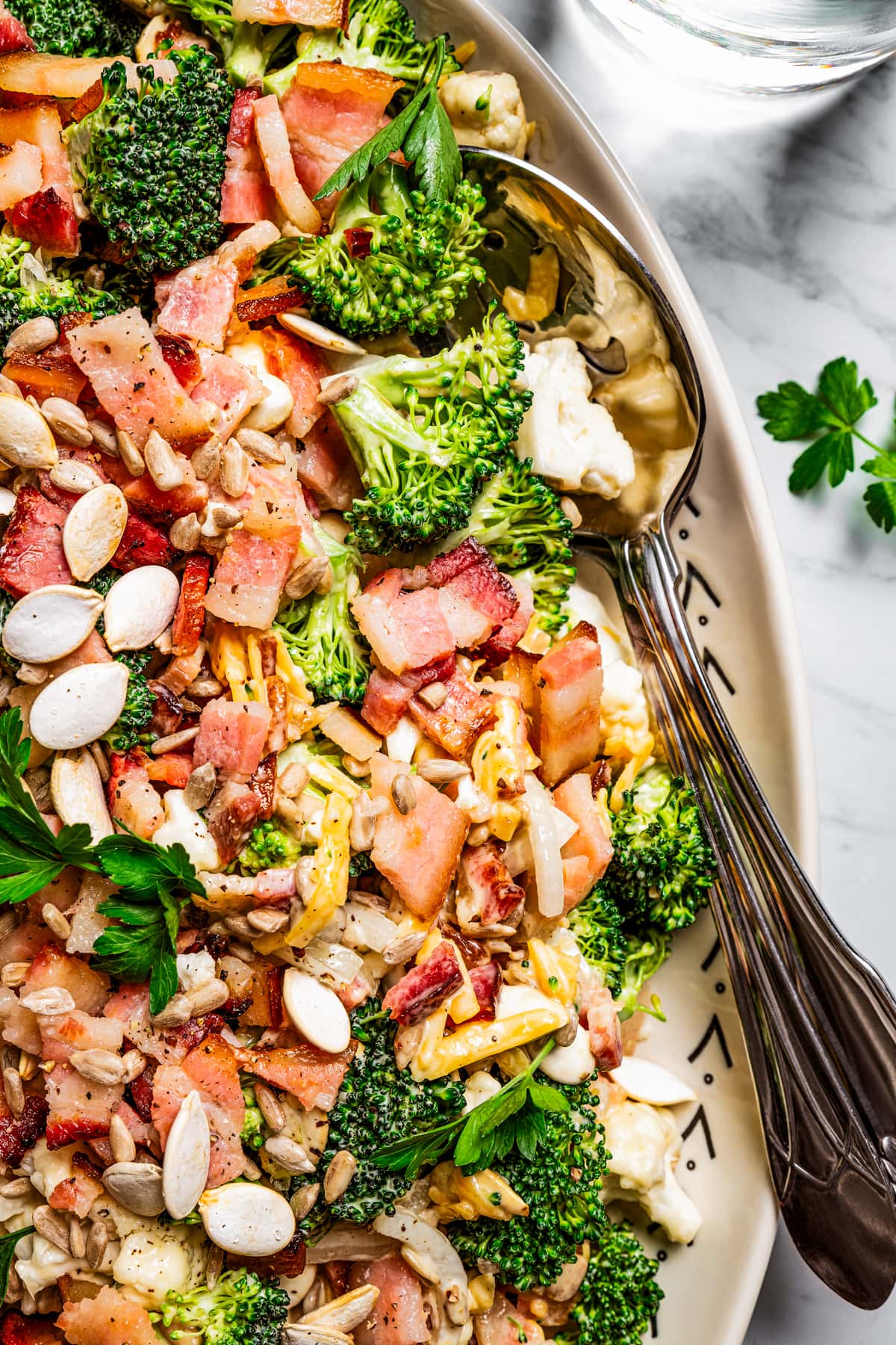 Broccoli cauliflower salad on a serving plate with a serving spoon.