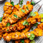 Overhead of chicken satay near a bowl of peanut dipping sauce