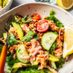 Chopped salmon salad in a bowl with a fork and a wedge of lemon.