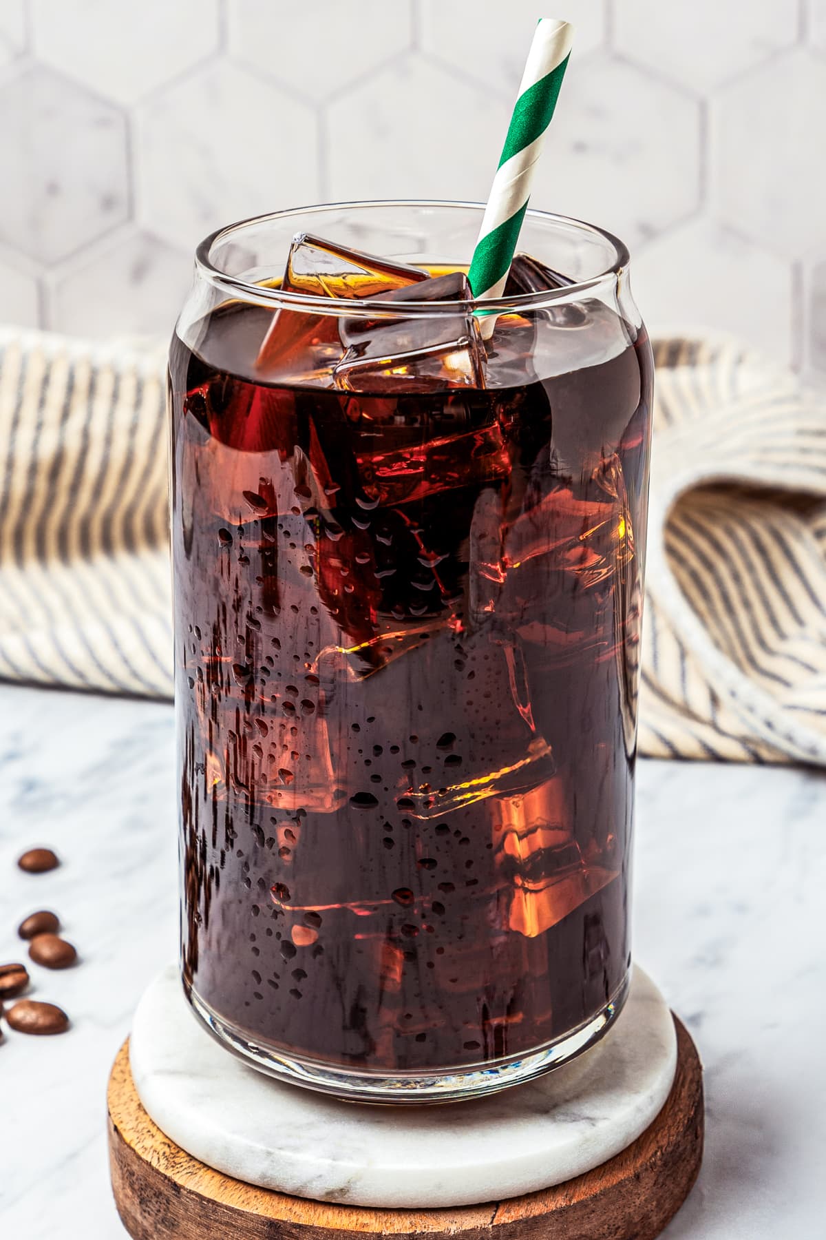 Close-up of iced Americano coffee served on a wooden and marble coaster.