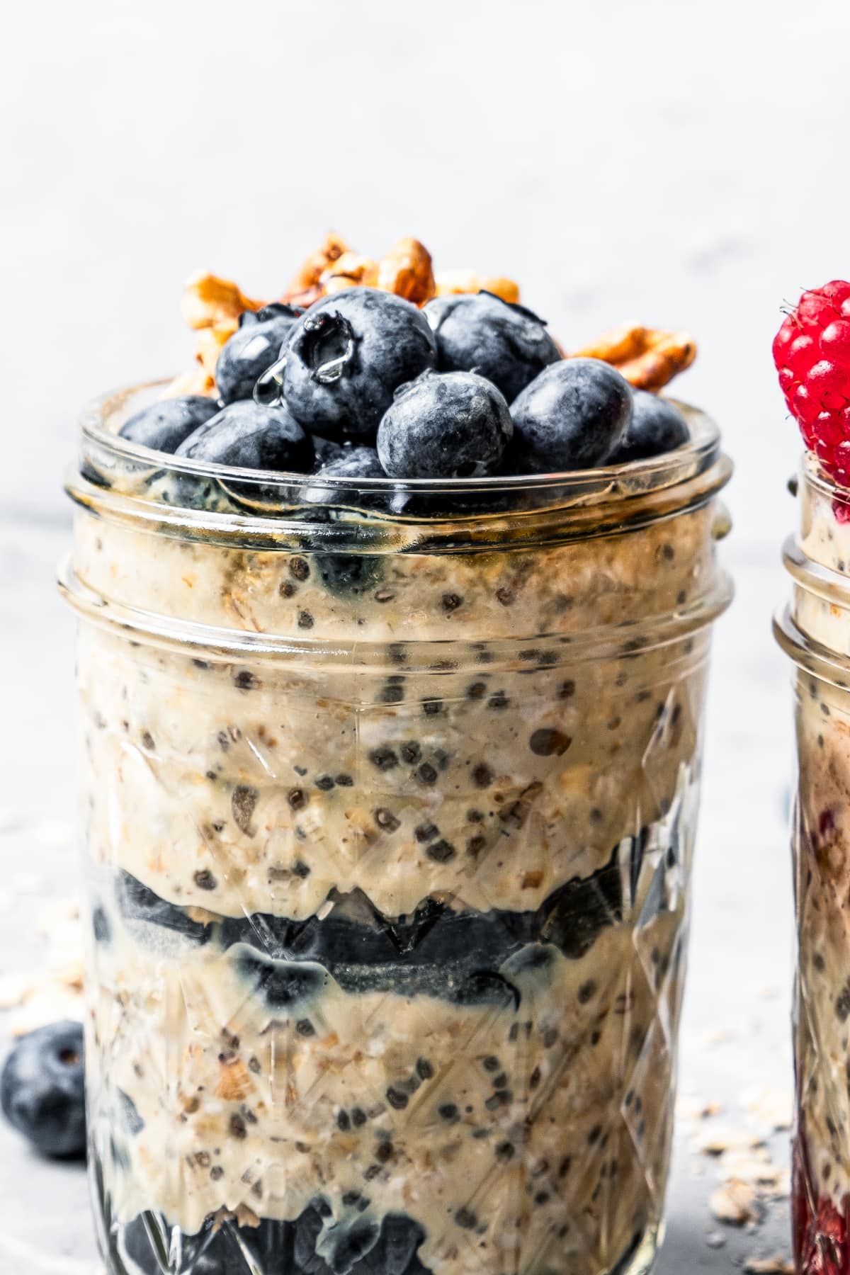 Close-up photo of protein oatmeal in a jar topped with blueberries and walnuts.