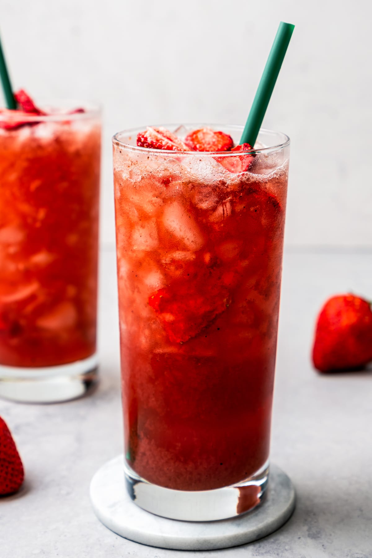 Two homemade Strawberry Acai Refreshers served in drinking glasses garnished with freeze-dried strawberries.