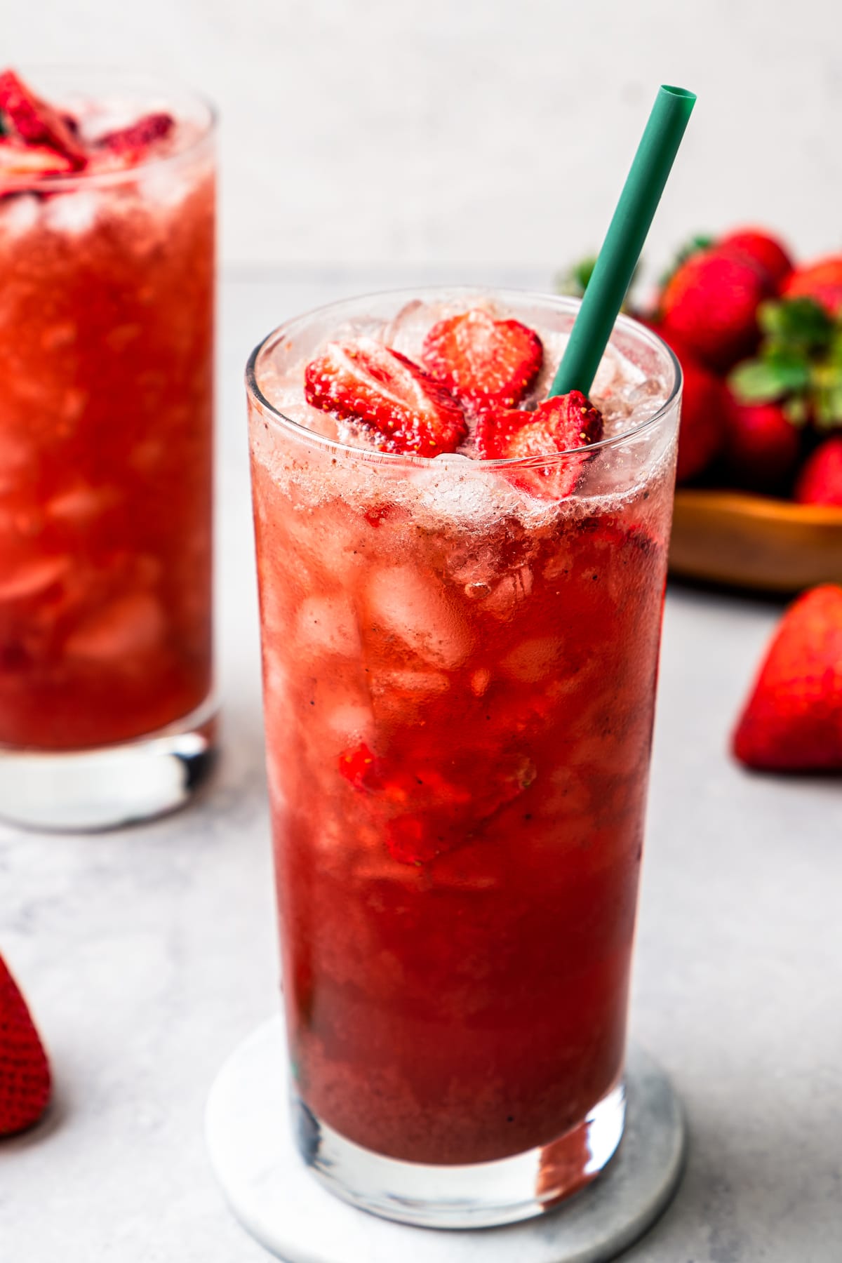 Two homemade Strawberry Acai Refreshers served in drinking glasses garnished with freeze-dried strawberries.