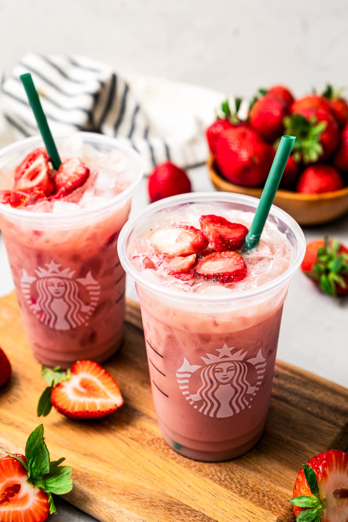 Homemade Starbucks pink drink in two plastic cups and garnished with dried strawberries.