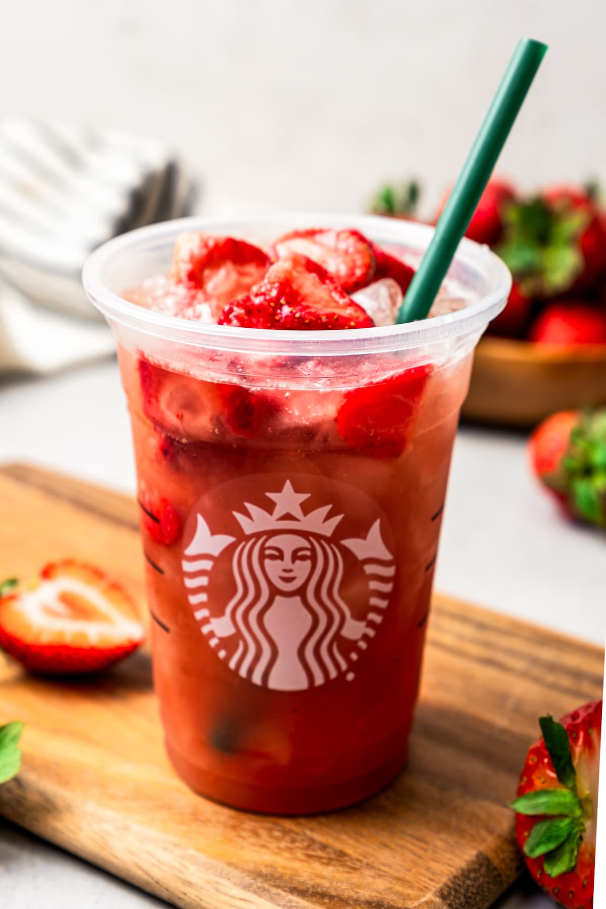 A strawberry acai refresher in a plastic cup garnished with freeze-dried strawberries.