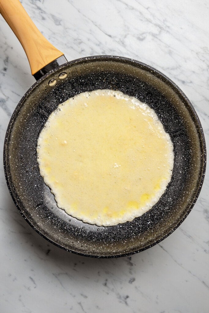 Cooking egg white-almond flour mixture in a skillet to make a wrap.